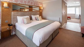 Garden Suite room with a king-size bed, upholstered headboard, and separate lounge area.