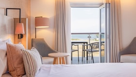 View of a Signature room at Bembridge Coast, with an open balcony door and the sea beyond