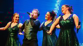 Four entertainers in green sparkly outfits performing on stage