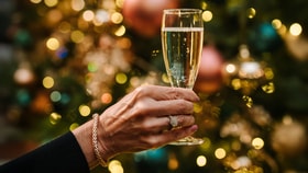 Close up of a glass of prosecco held in front of a christmas tree