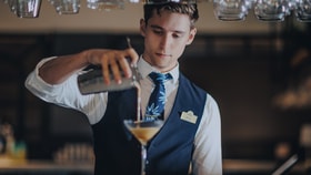 A bartender pours a cocktail from a shaker