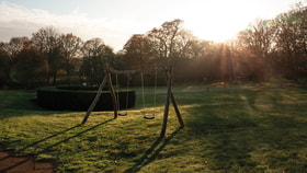 A swing set on the grounds of Gunton Hall at sunset
