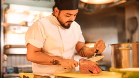 Chef carving freshly roasted meat in an open kitchen