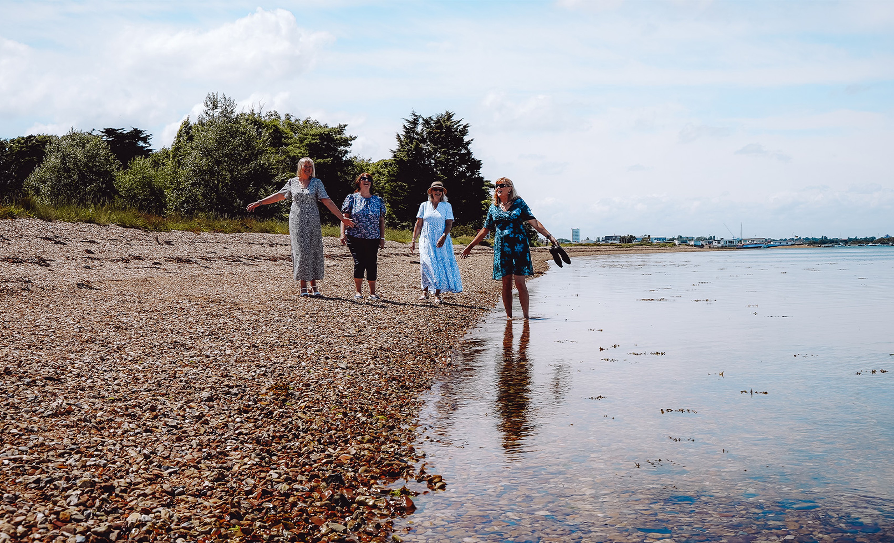 A group of people walking along the sandy beach at Sinah Warren, enjoying the sunny day and ocean views.