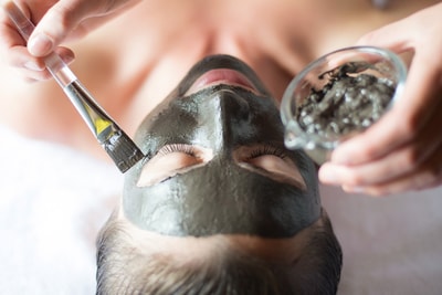 Person applying a face mask to a woman's face