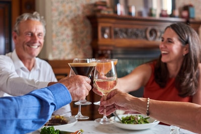 Guests making a toast over a delicious meal that they share in the Brasserie32 at Thoresby Hall Hotel