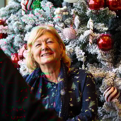 A woman smiling in festive dress in front of a christmas tree