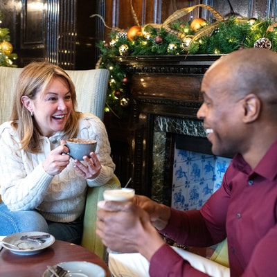 Two guests smiling at each other with hot drinks in hand