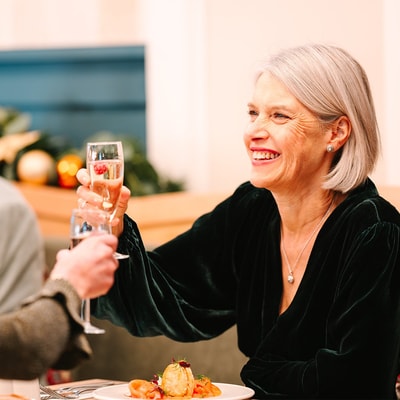 A woman smiling as she toasts with another guest