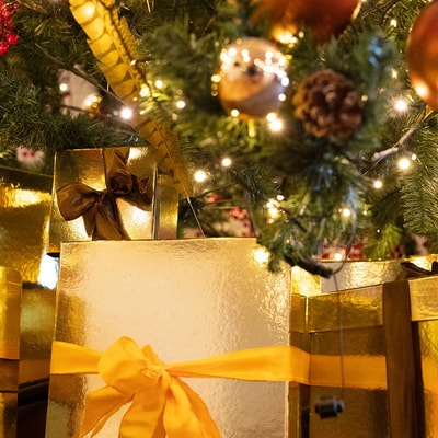 Assorted gold and brown presents neatly arranged under a festive Christmas tree.