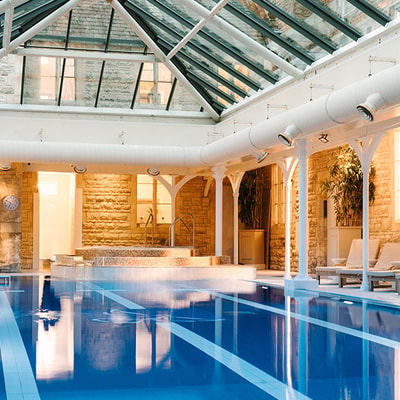 Indoor spa pool with relaxation loungers, glass roof and luxury wellness facilities.