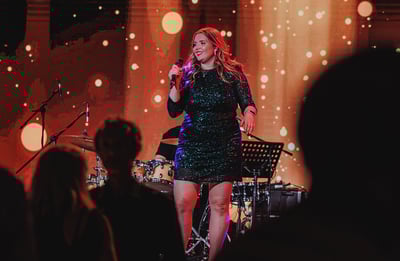 Performer on stage in front of a red sparkly background