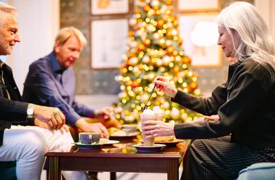 A group enjoying hot drinks in front of a christmas tree