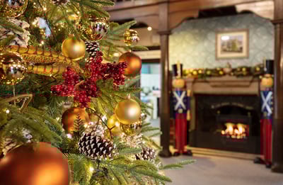 Close up of a Christmas tree with a fireplace in the background and a pair of nutcrackers