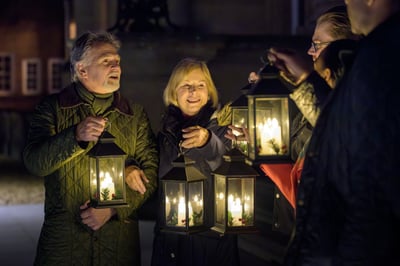A group of people holding lanterns, smiling and talking