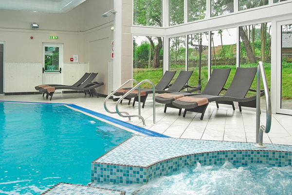 Indoor pool with bright, airy surroundings and comfortable lounge seating.