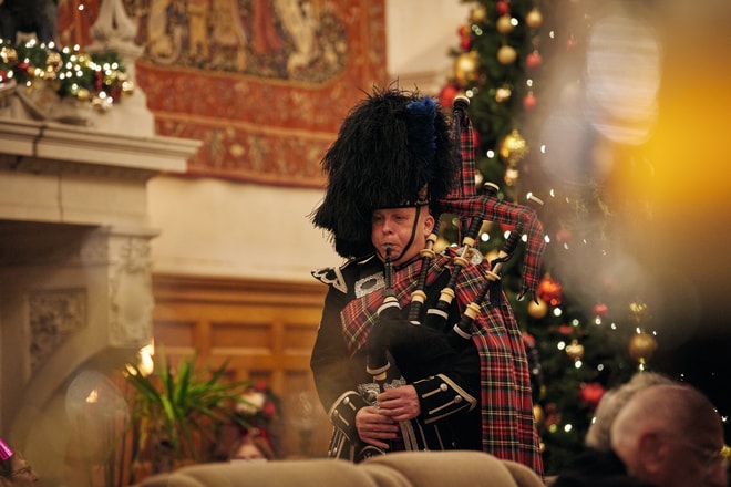 A piper playing the bag pipes walking through a crowd of people