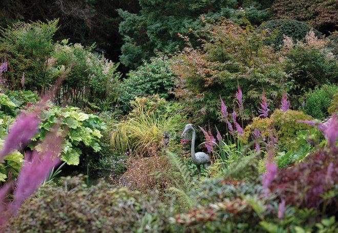 Plants and flowers surrounding a herring statue on the grounds at Cricket St. Thomas