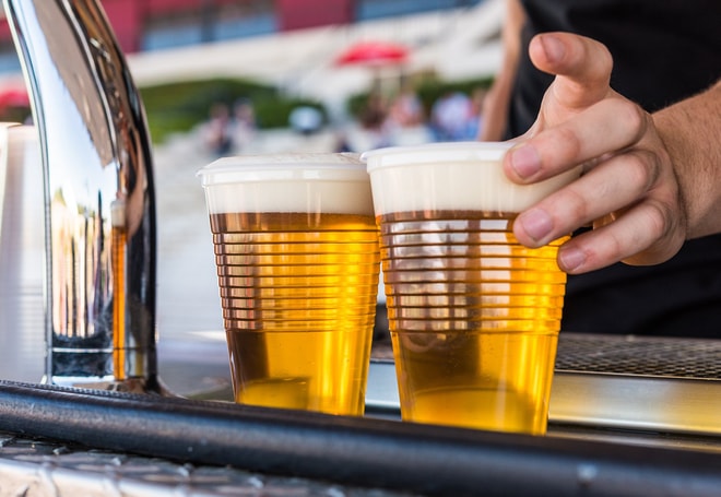 Two beers being placed on a counter at a food festival