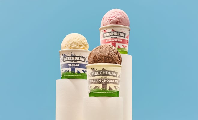 Three cups of Beechdean ice cream - vanilla, strawberry, and Belgian chocolate - stacked on white pedestals against a blue background.