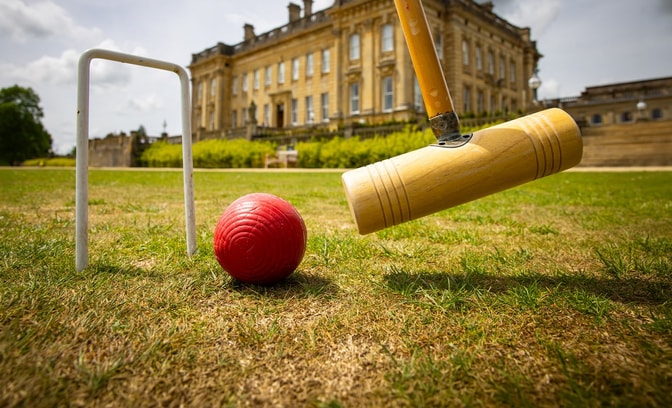 Close up of a croquet ball being putted through a hole