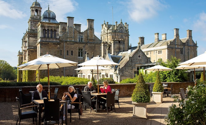 Some guests are enjoying drinks and snacks on the terrace on a warm day at Thoresby Hall Hotel