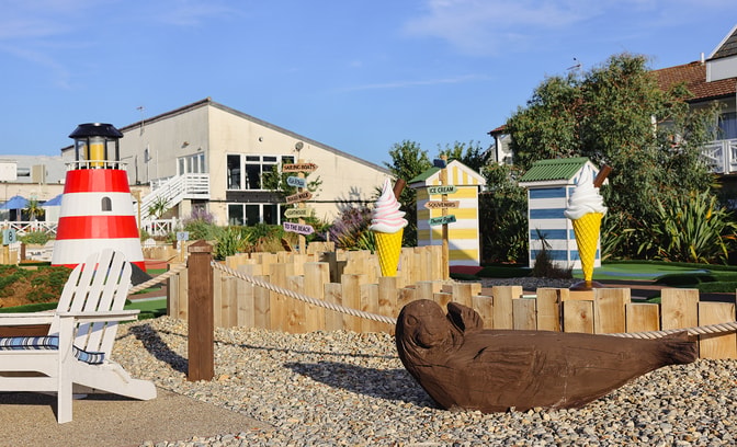 Brightly coloured decor on the grounds at Corton, including a lighthouse, some miniature beach huts, two XL ice cream cones and a wood carved seal