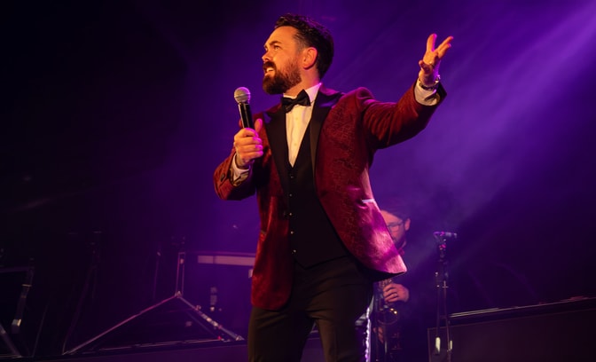 ray quinn singing on stage in suit