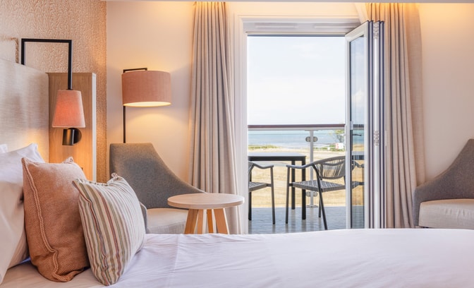 View of a Signature room at Bembridge Coast, with an open balcony door and the sea beyond