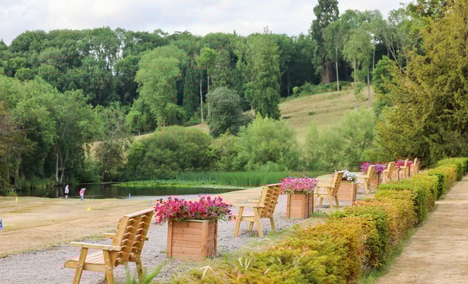 The grounds of Holme Lacy House featuring several benches lined up with flower pots in between