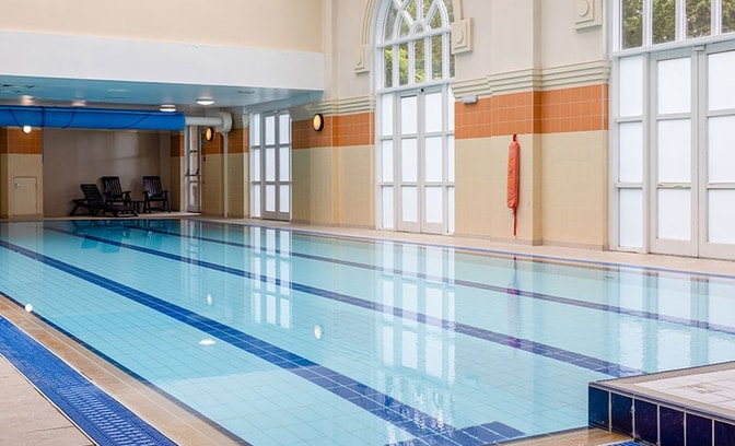 Indoor swimming pool with high ceilings, natural light and relaxing leisure amenities.