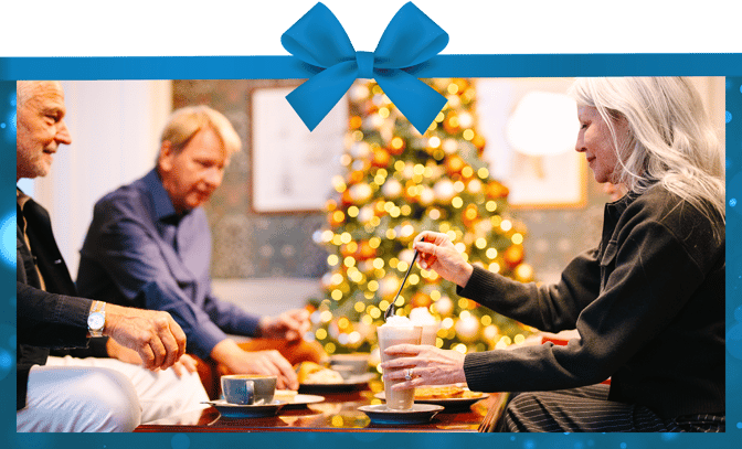 A group enjoying hot drinks in front of a christmas tree