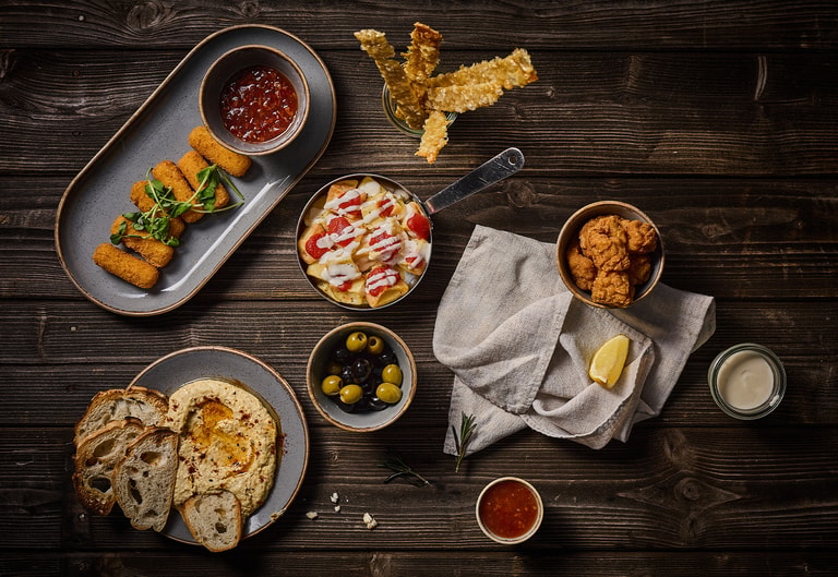 Gasto dining small dishes, including hummus and bread, croquettes, olives and loaded tortilla chips