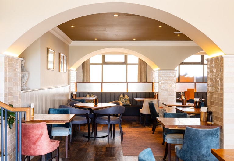 Brightly lit gastropub style restaurant with several tables and chairs