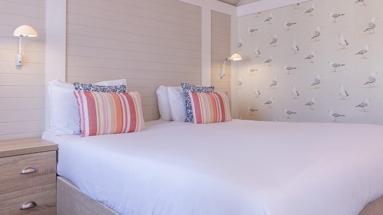 Clifftop Lodge - Bedroom with coastal-themed décor perfectly ties together with ultimate comfort, creating a relaxing space that feels like a true seaside retreat.