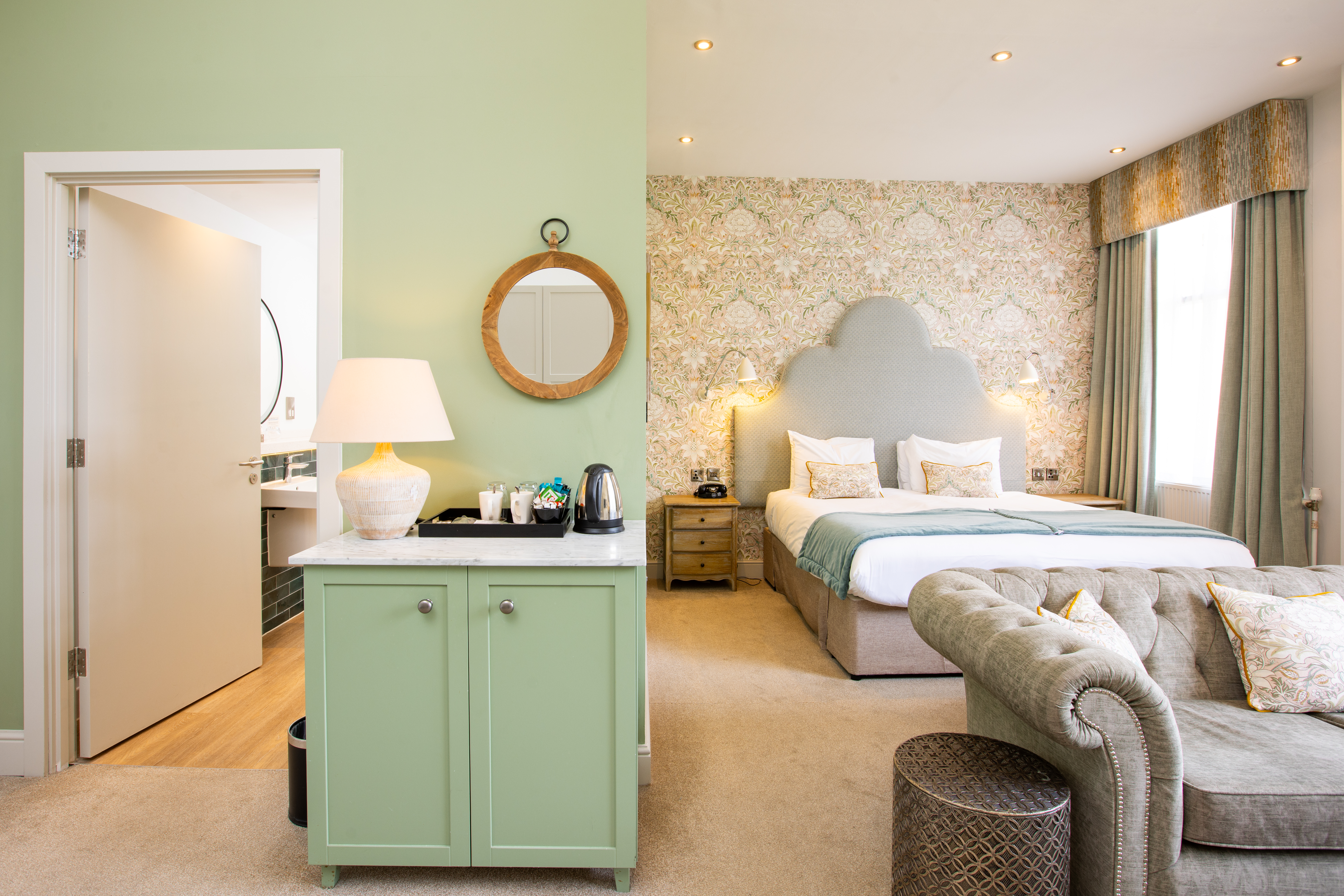 Large bedroom with a double bed, sofa, cabinet with tea tray and a door leading to a bathroom