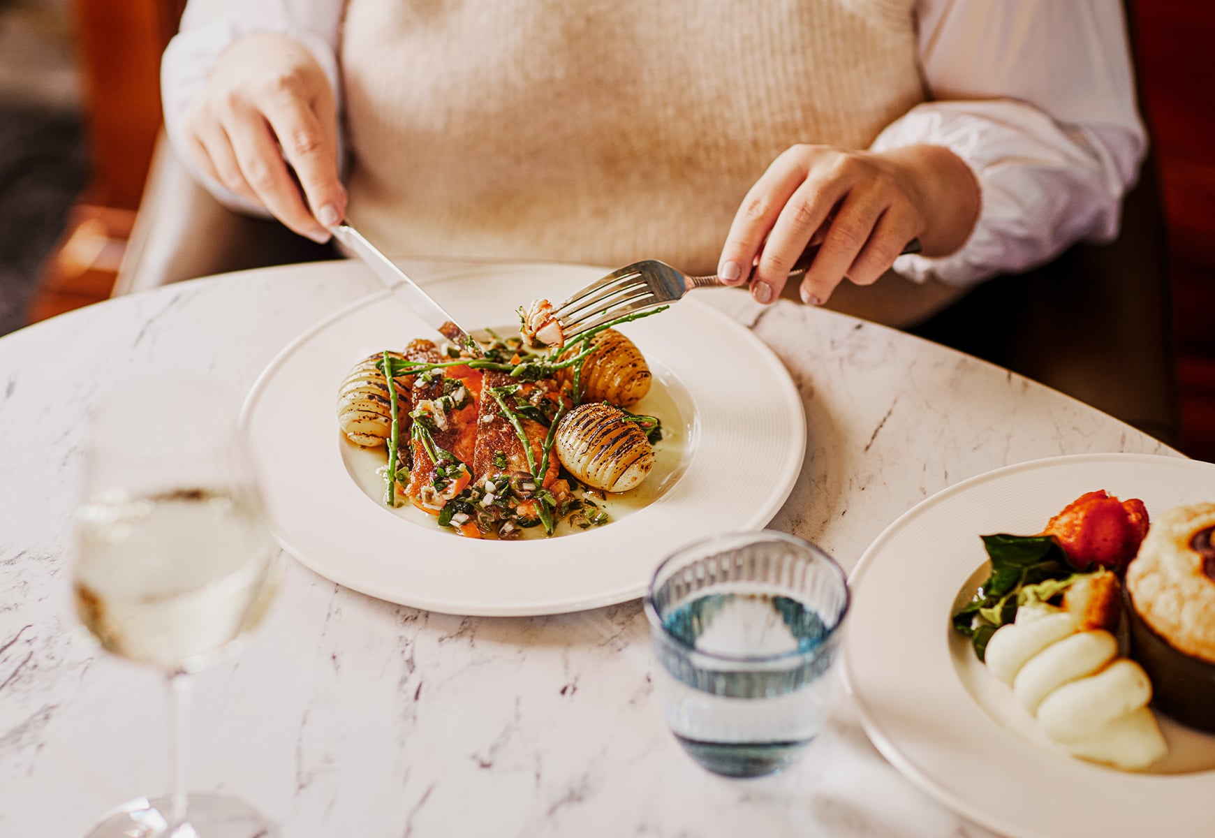 A lady cutting into a plate of loch reared trout
