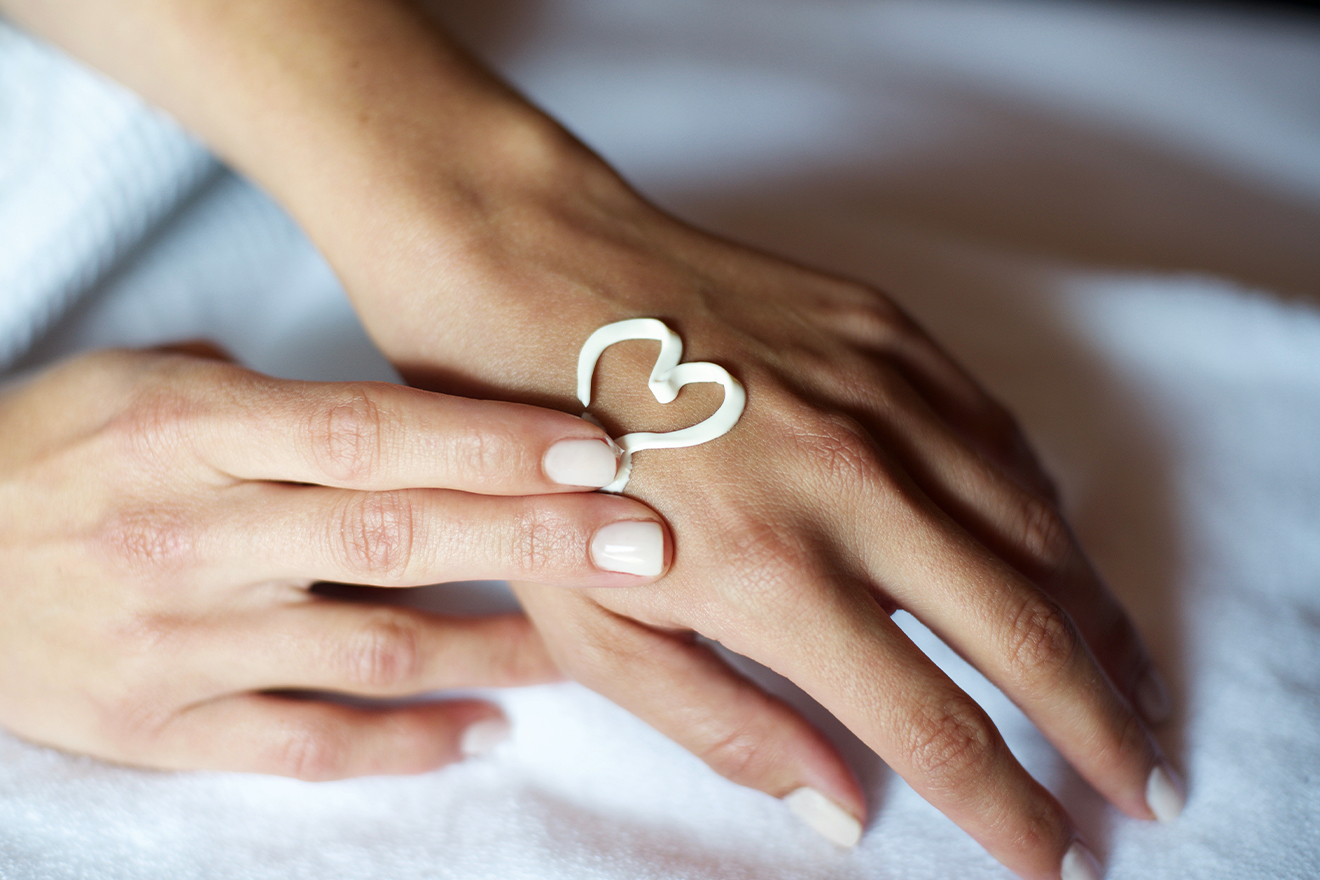 Close up of a person's hand with a heart drawn with cream