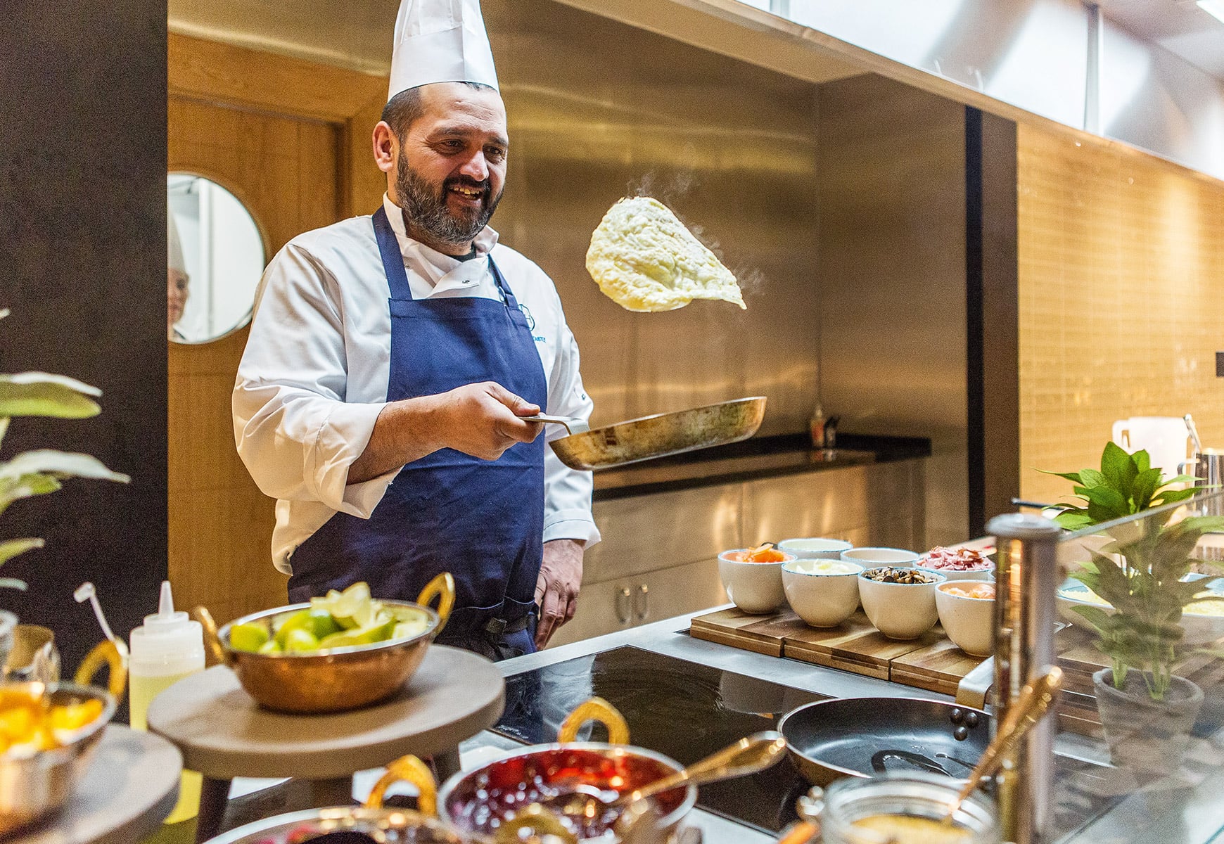 Chef flipping a flat bread and smiling behind a griddle